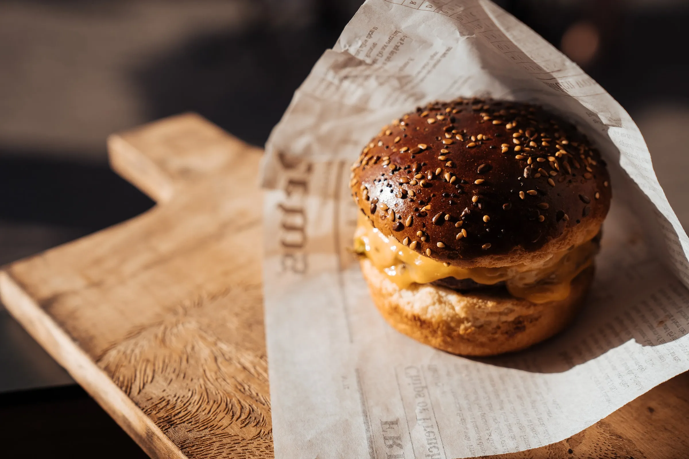 Een hamburger van Angus Grand Cru in papier op een houten plankje