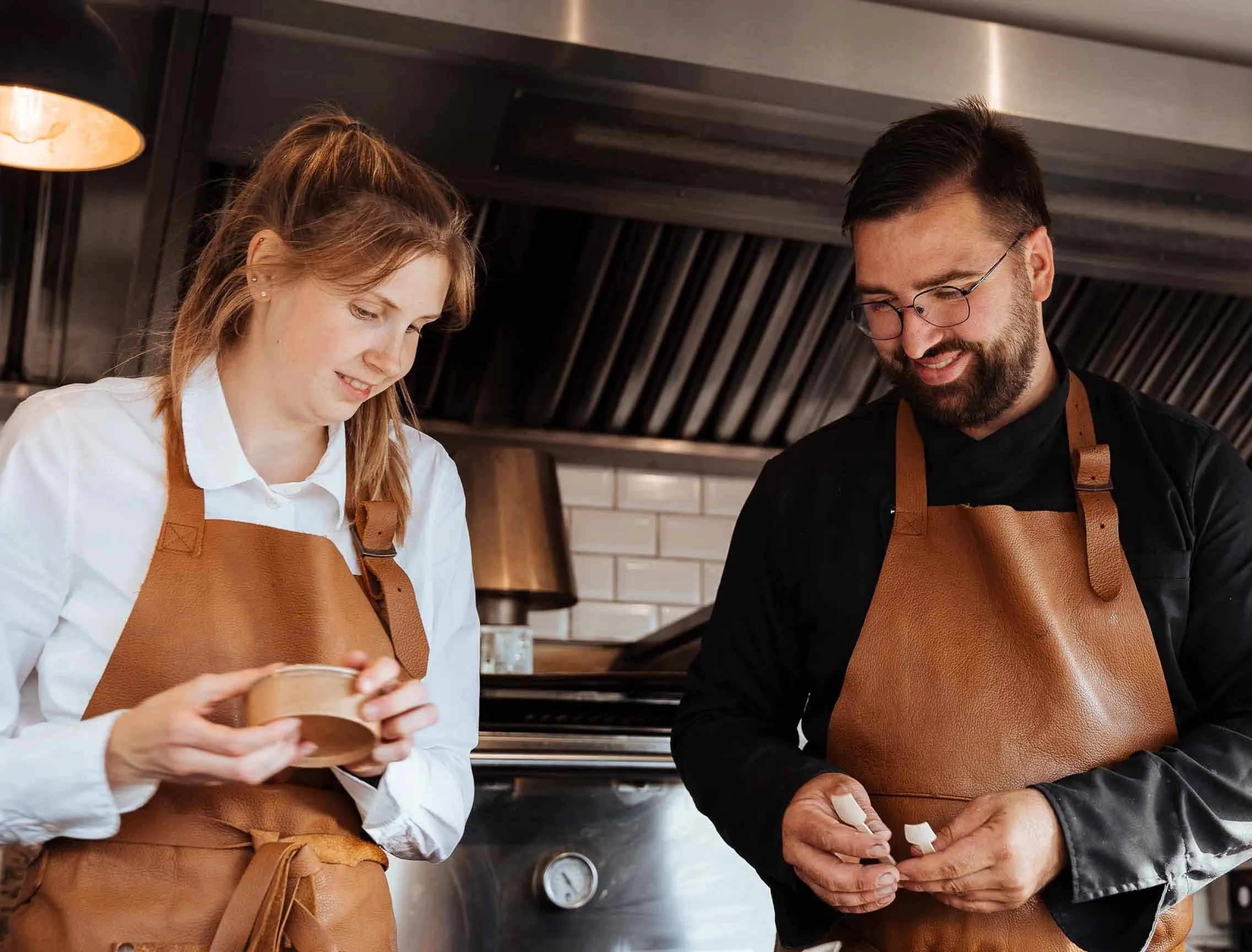 Twee medewerkers in leren schorten maken hapjes klaar in de foodtruck